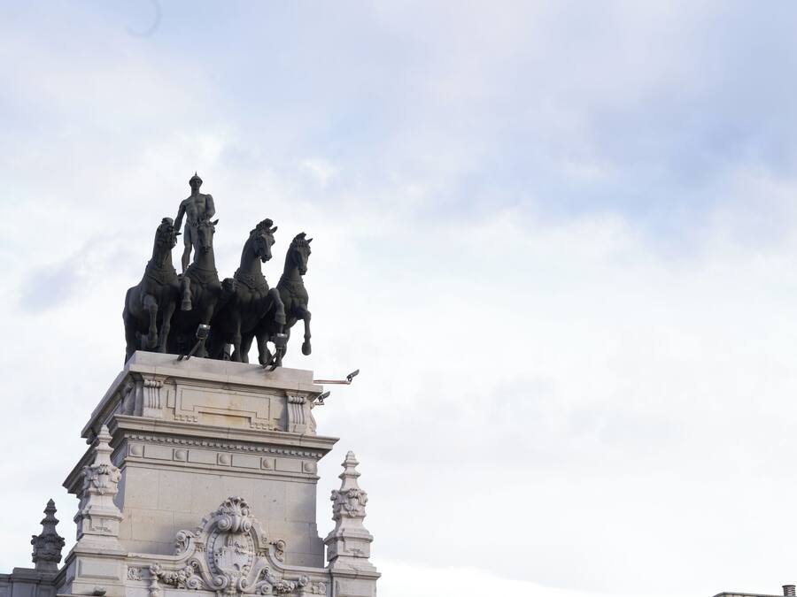 A statue of a man on horseback atop a classical building with ornate architectural details.