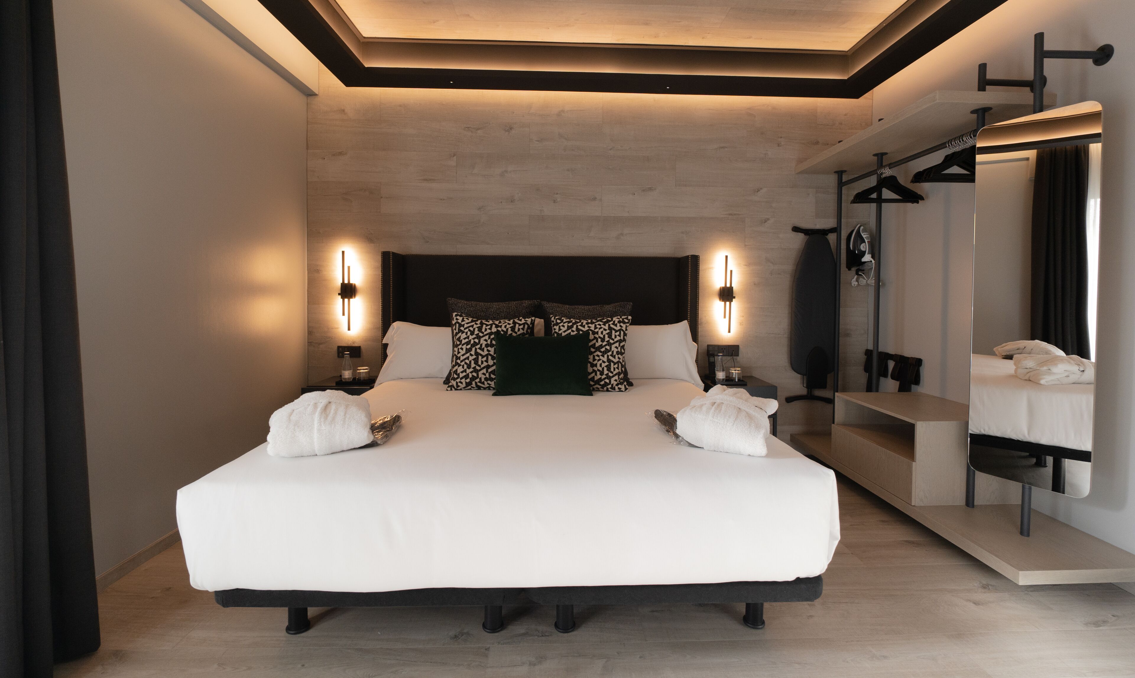 Una habitación de hotel moderna con una cama grande, lámparas de noche, un espejo y un armario.