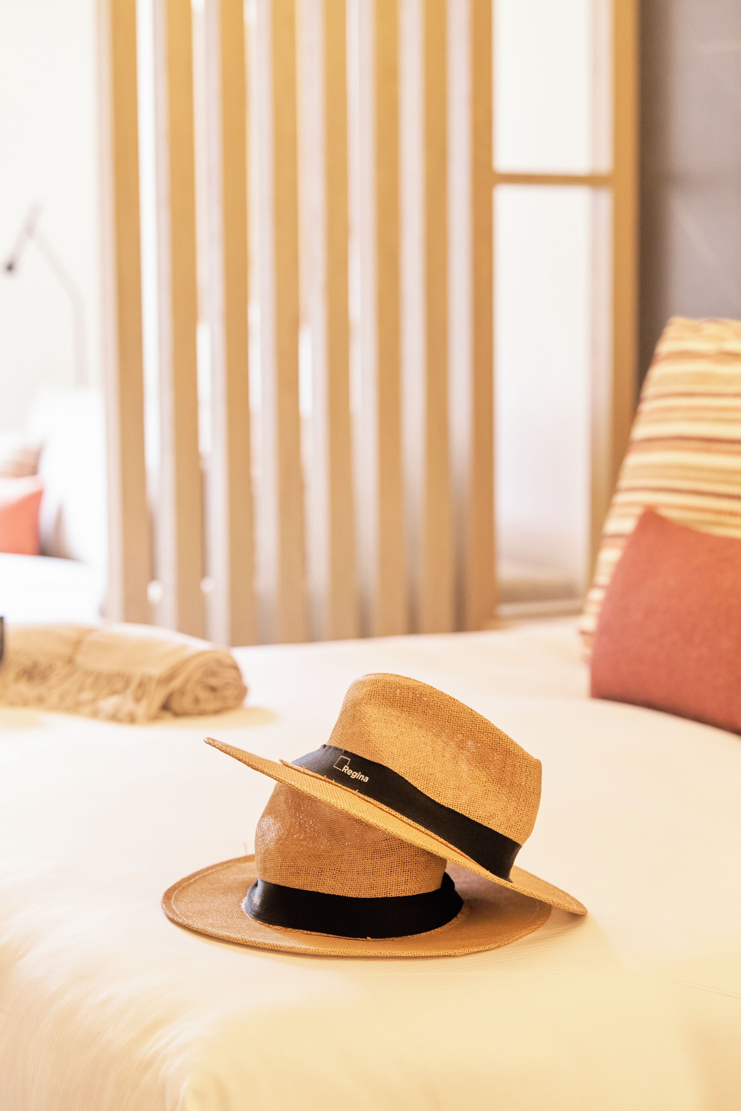 Un sombrero de paja con una cinta negra sobre una cama.