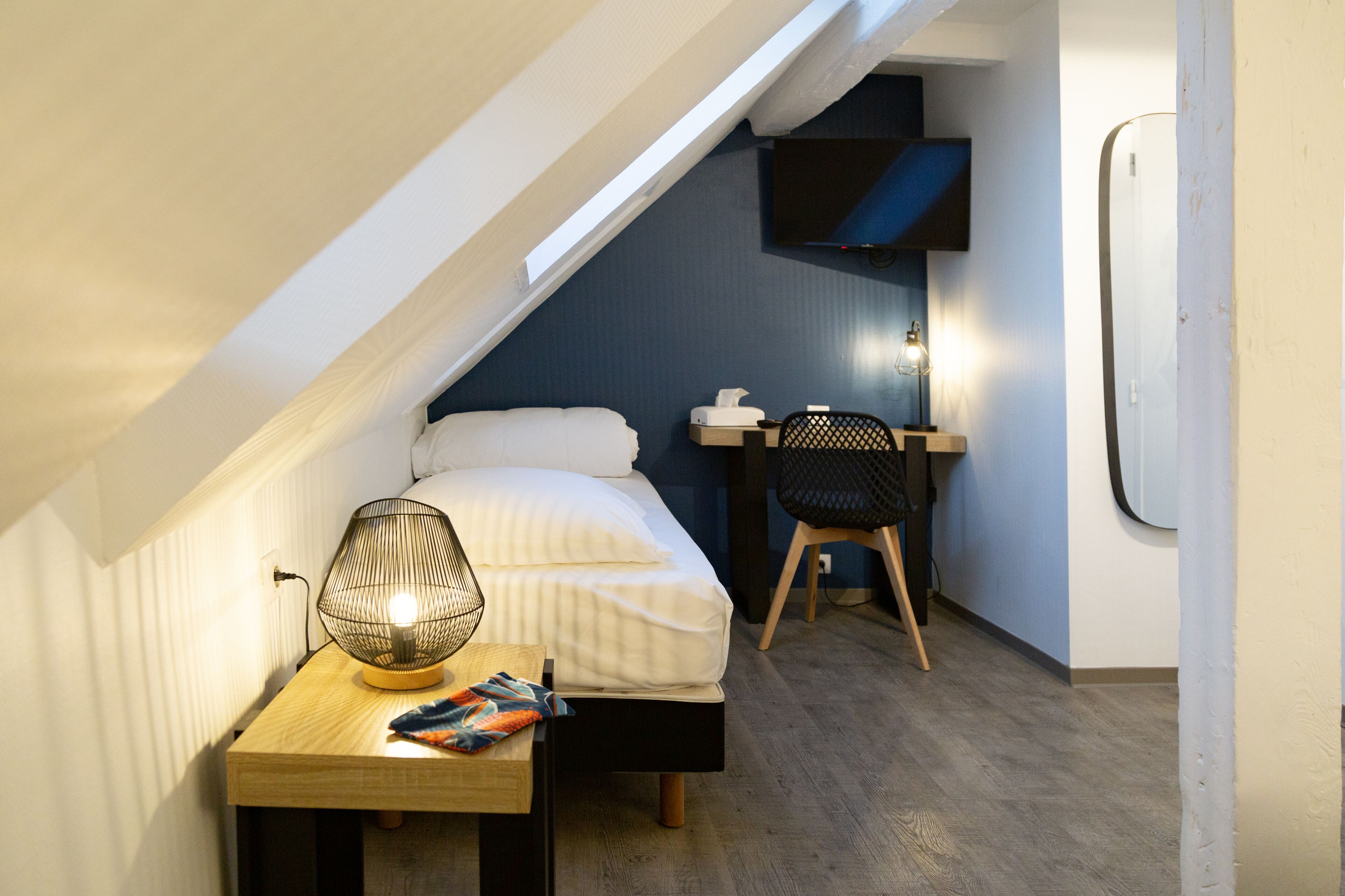 Un dormitorio pequeño con cama, mesita de noche, lámpara y escritorio con silla.