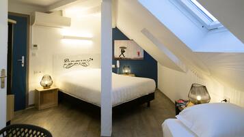 Un dormitorio con tragaluces, una cama, lámparas de noche y una pared con un letrero decorativo.