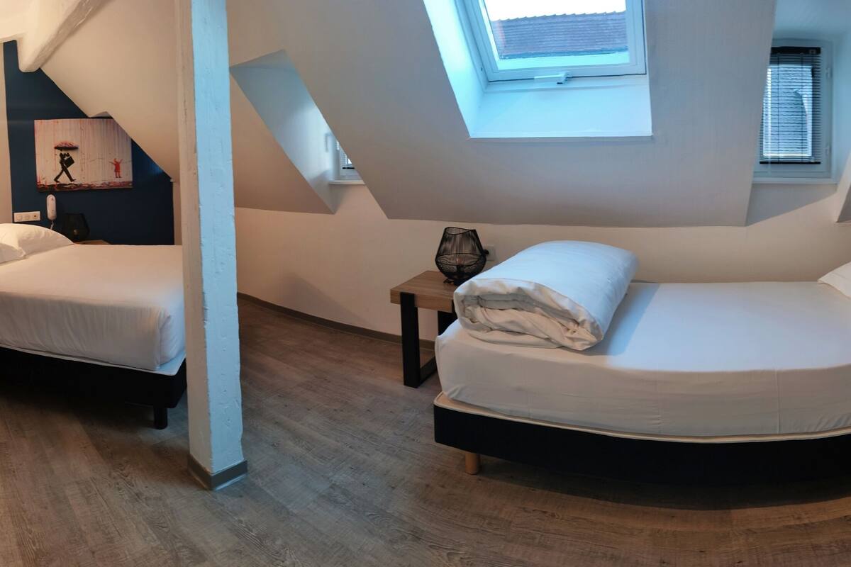 A compact bedroom with two beds, a skylight, and a small window.