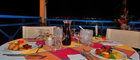 A dining table set with plates of food, glasses, and a candle.