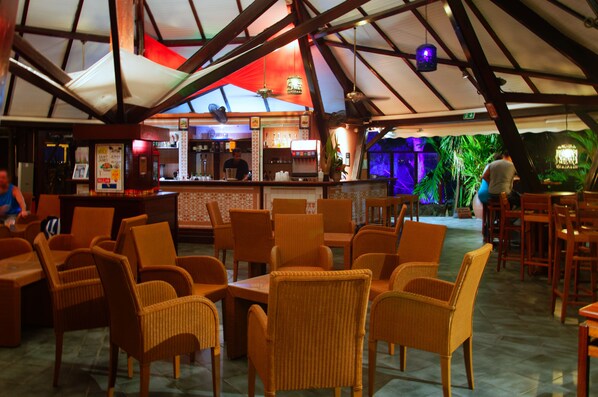 Un restaurante con sillas de mimbre y una zona de bar.