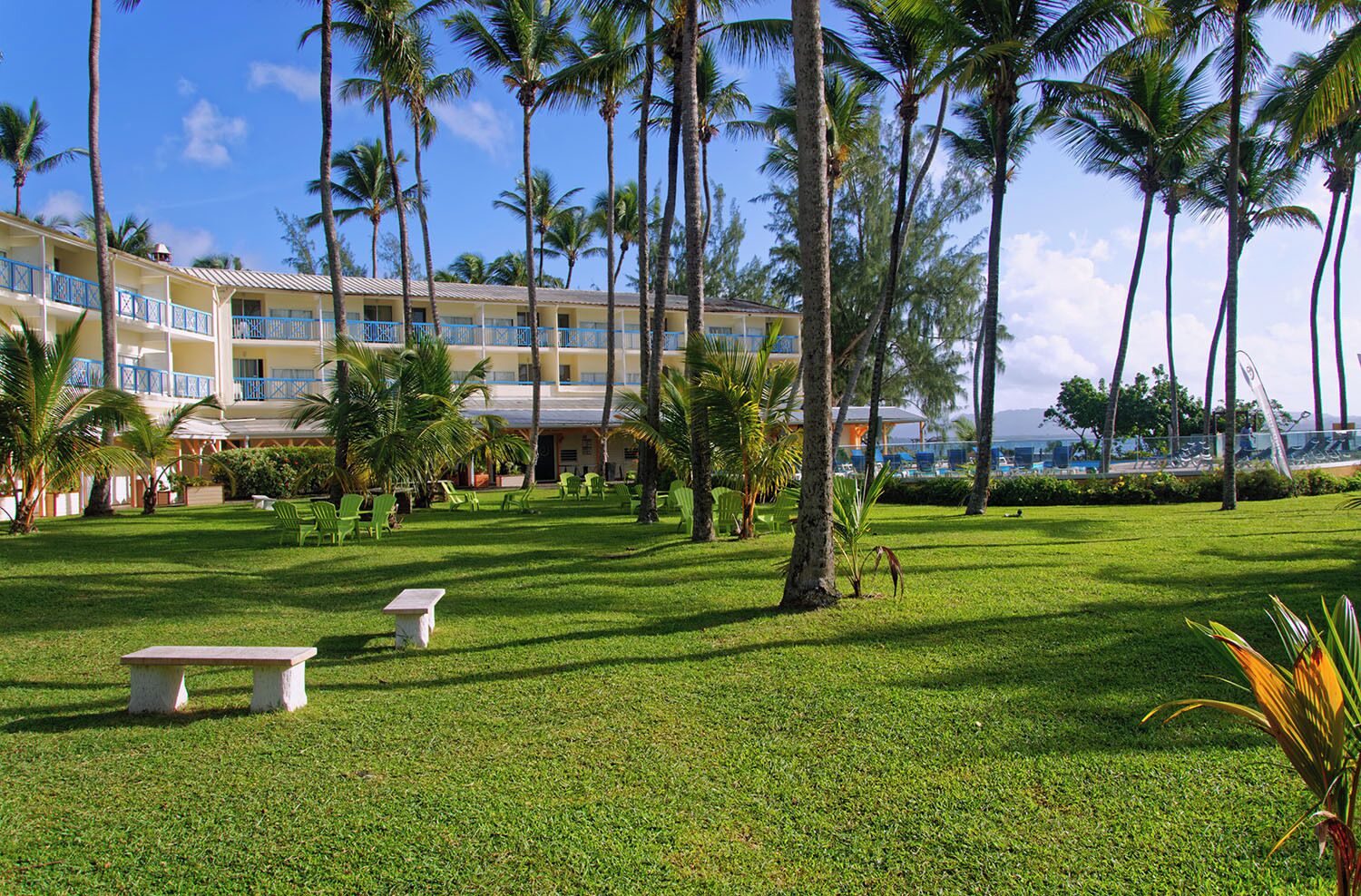 Un resort con piscina, palmeras y un edificio con varios balcones.
