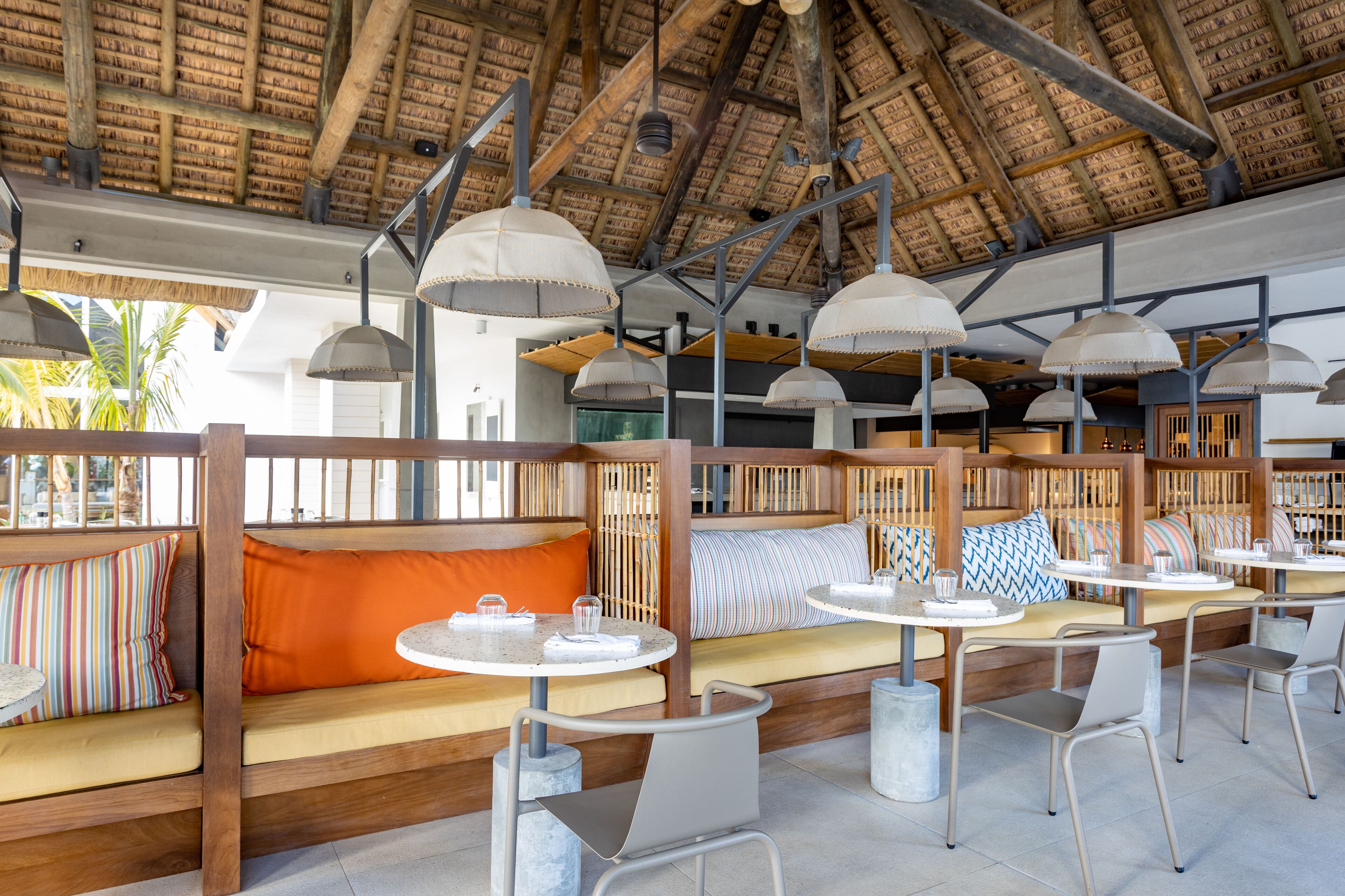 A restaurant with wooden seating, tables, and hanging lamps.