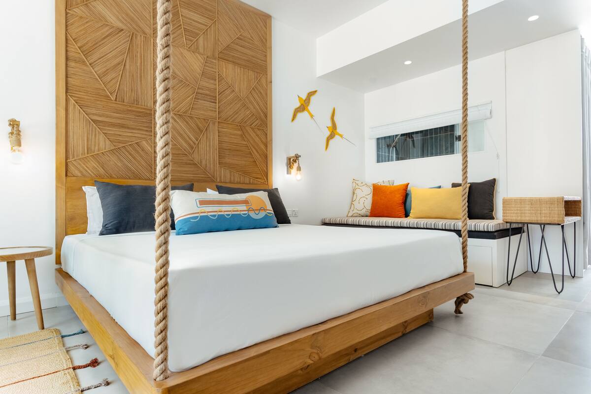 Un dormitorio moderno con una cama colgante, cabecera de madera y detalles decorativos en la pared.