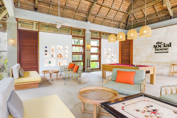 Un amplio espacio interior con mesa de billar, cómodos asientos y mesa de futbolín.