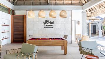 Una mesa de billar en una habitación con techo alto y tejado de paja.