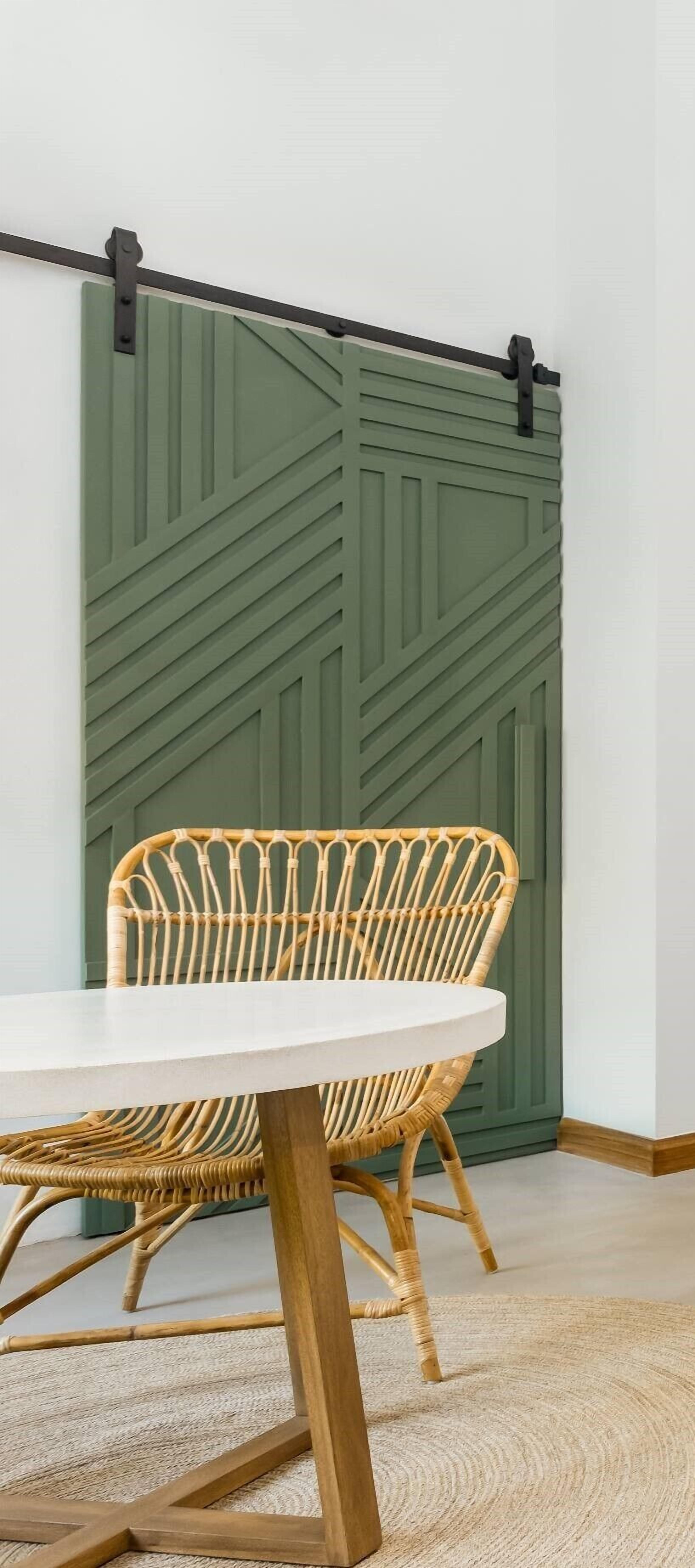 A room with a white table, a wicker chair, and a green sliding door.
