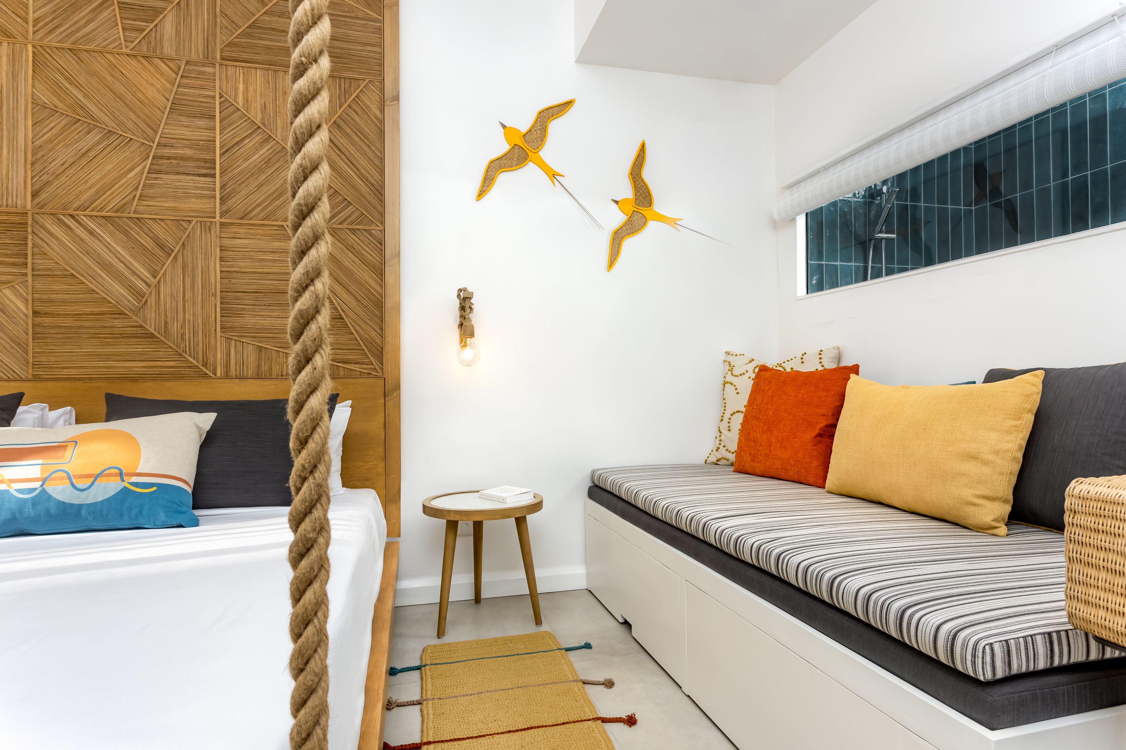 Une chambre à coucher moderne avec une tête de lit en bois, un canapé à rayures et un luminaire fixé au mur.