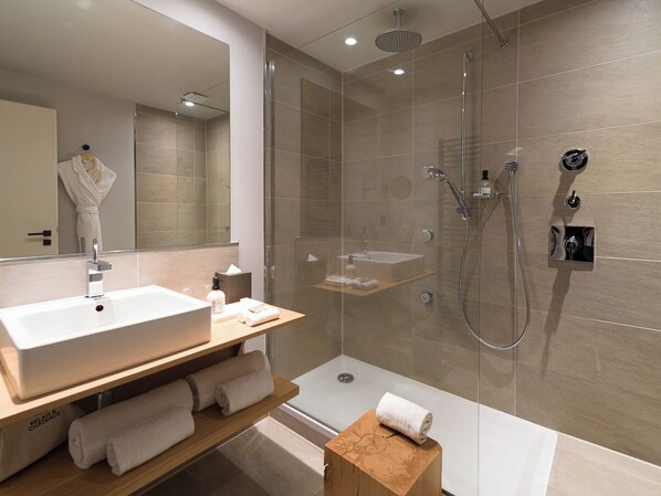 Ein modernes Badezimmer mit großem Spiegel, Waschbecken, Dusche und einem Holz-Waschtisch.