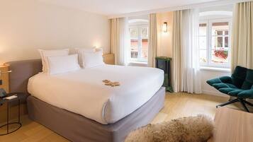Habitación de hotel con una cama grande, un escritorio, una silla y vistas al exterior.
