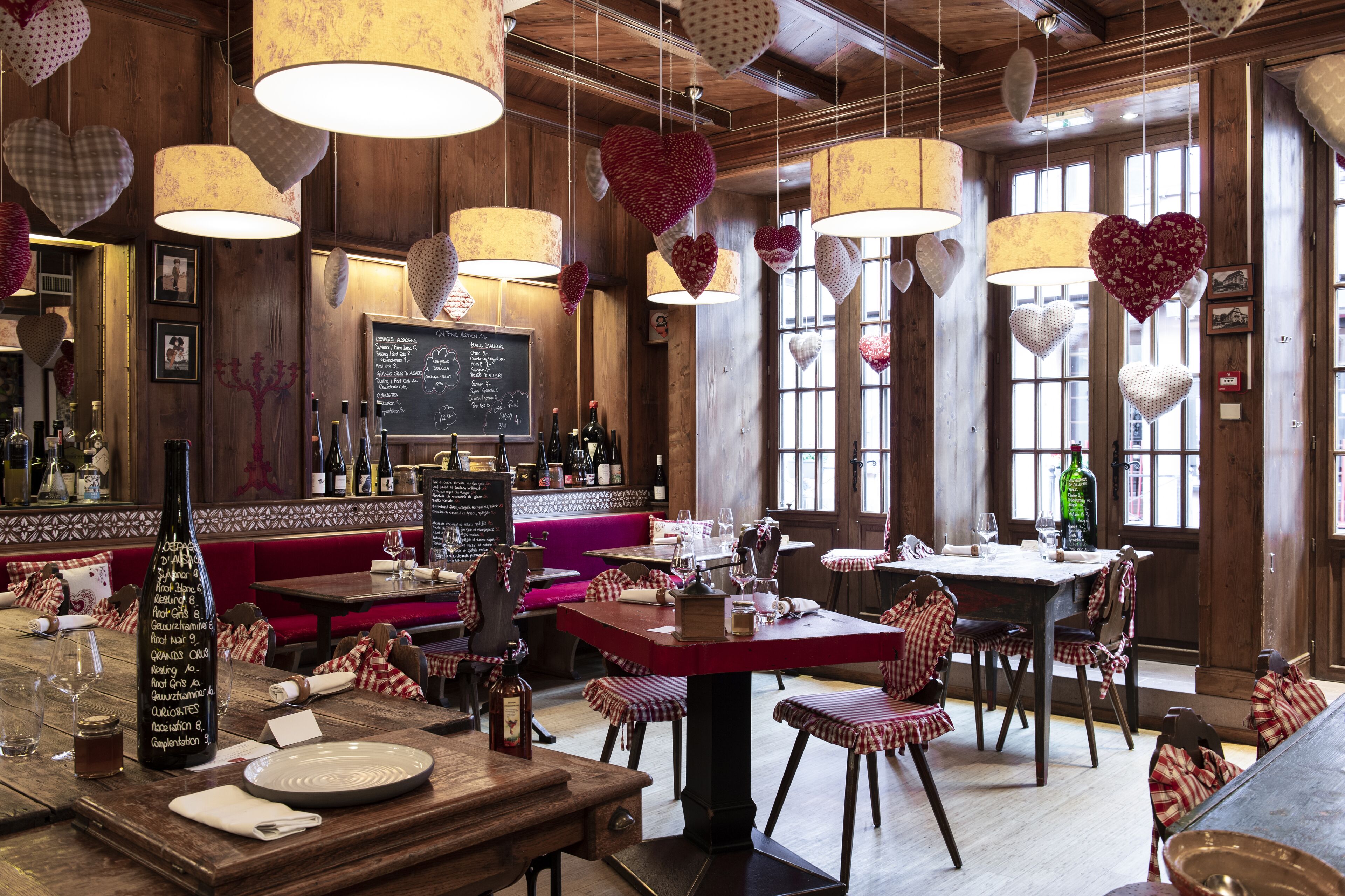 A restaurant with wooden interiors, heart-shaped hanging decorations, and a chalkboard menu.