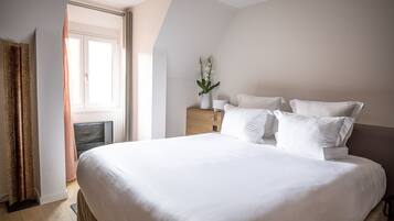 Una habitación de hotel con una cama grande, una mesita de noche con lámpara y una ventana con cortinas.