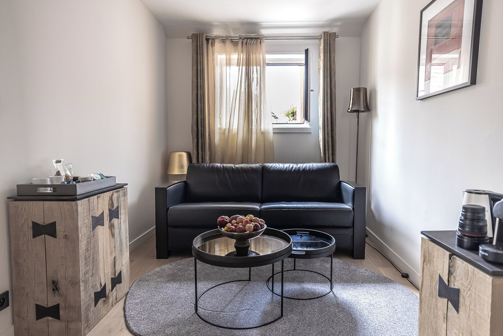 Una sala de estar moderna con un sofá, una mesita de centro con fruta, un mueble de madera con tiradores de lazo y una lámpara.