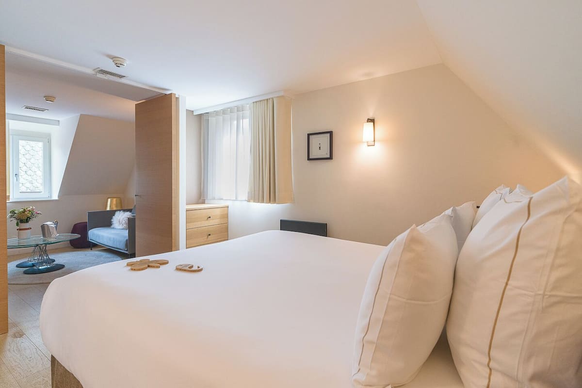 A hotel room with a large bed, a desk, a chair, and a window with curtains.