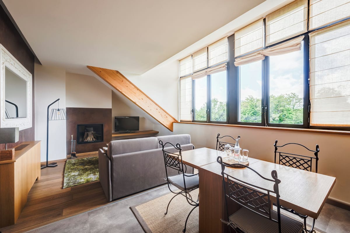 Una sala de estar moderna con comedor, chimenea y ventanas amplias.