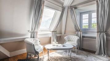 Ein Zimmer mit einer weißen Couch, einem runden Tisch und einem großen Fenster mit Vorhängen.
