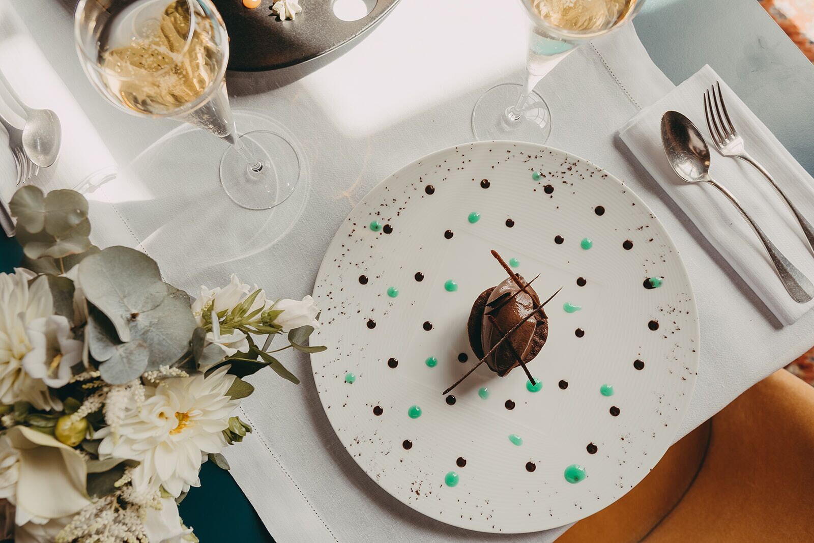 Ein Tisch ist gedeckt mit einem Dessertteller, Weingläsern und Besteck.