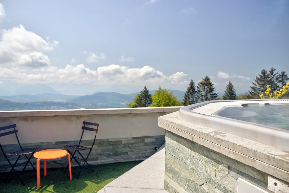 Un jacuzzi en la azotea con vistas a montañas y árboles.