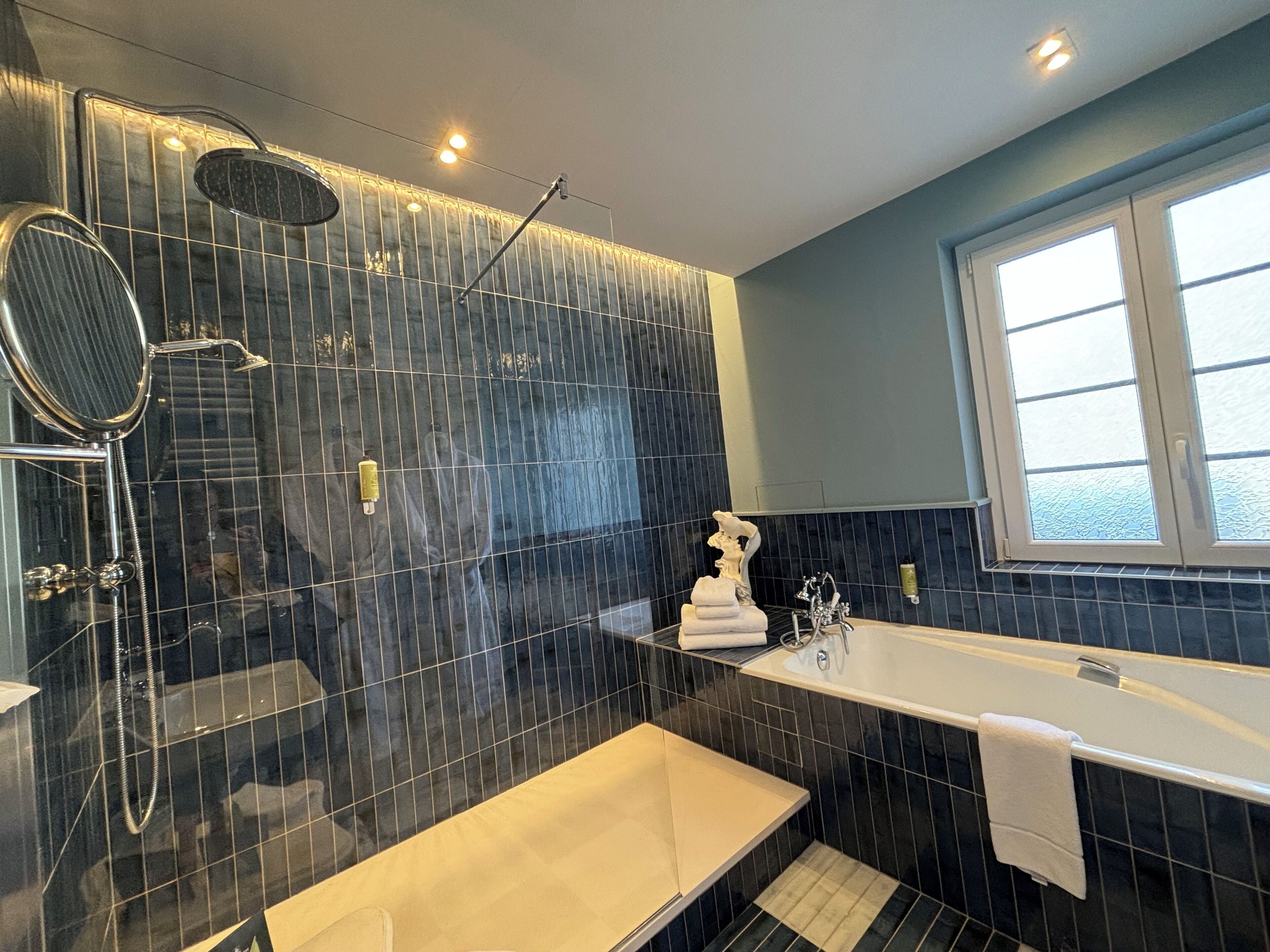 A modern bathroom with a bathtub, shower, and a vanity with a mirror.