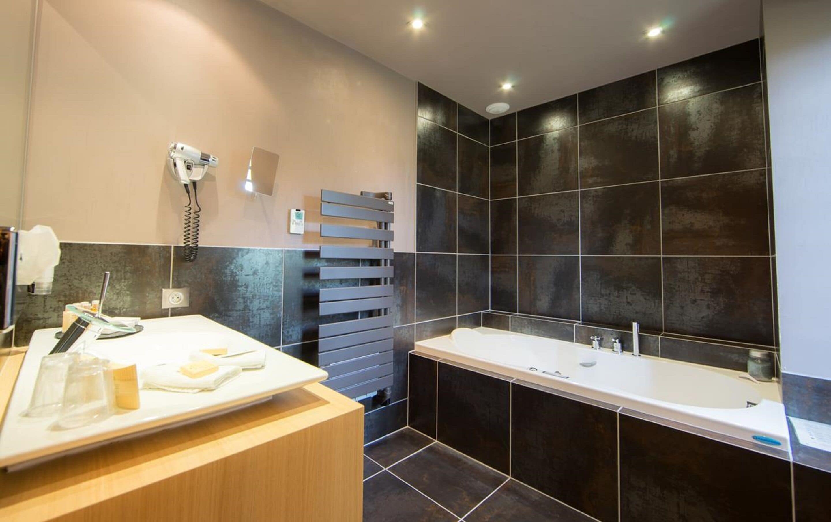 A modern bathroom with a large bathtub, a vanity with a mirror, and a towel rack.