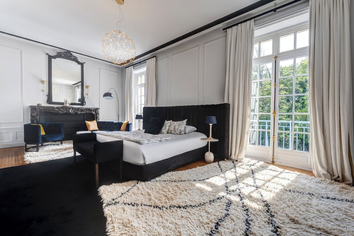 Un dormitorio con una cama grande, un aparador, un tocador y una ventana con cortinas.