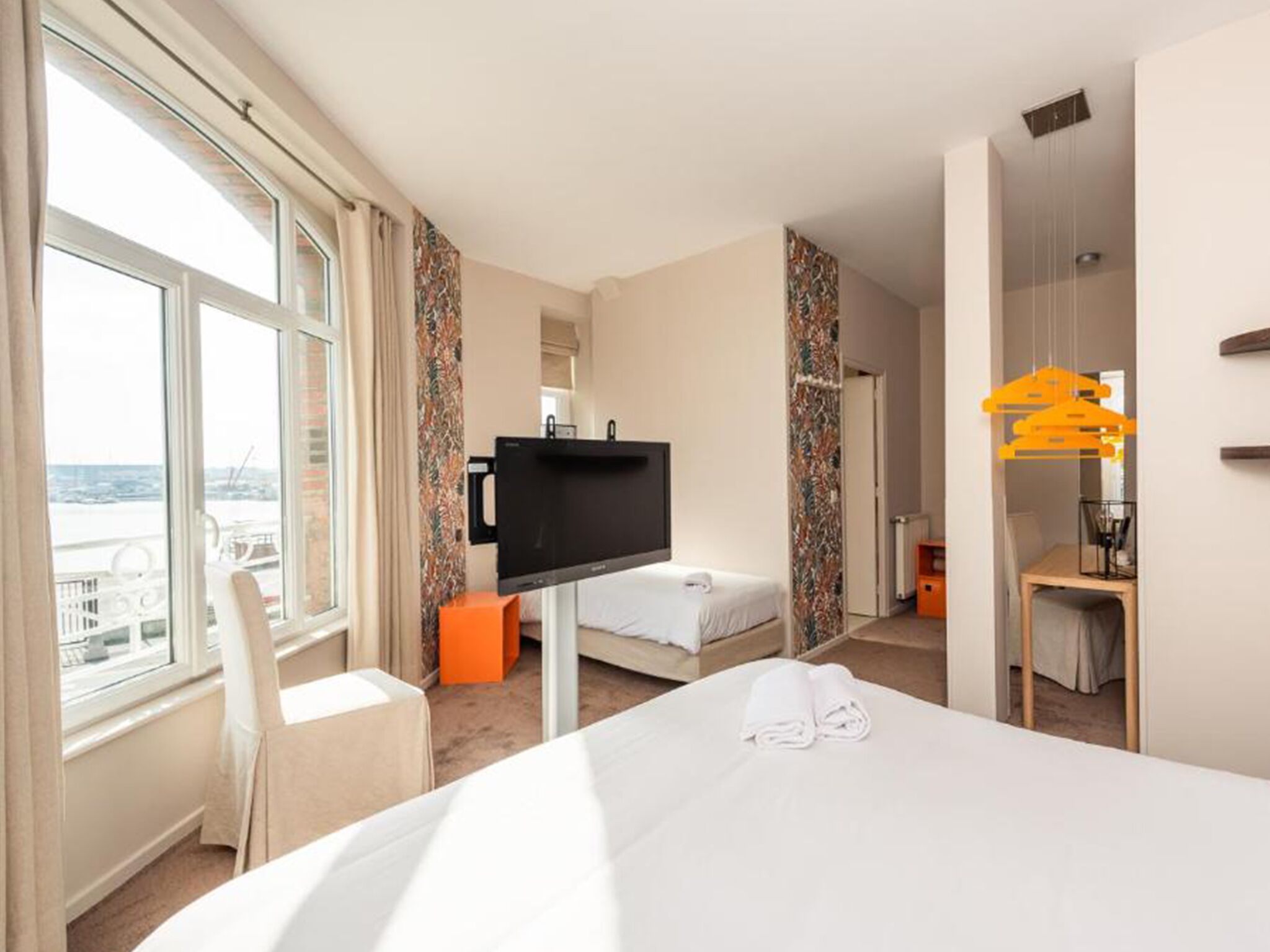 Una habitación de hotel con cama, televisión, escritorio y silla.