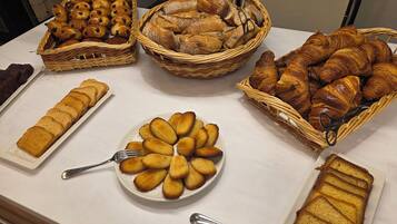 A buffet table with various baked goods including croissants, bread, and pastries.