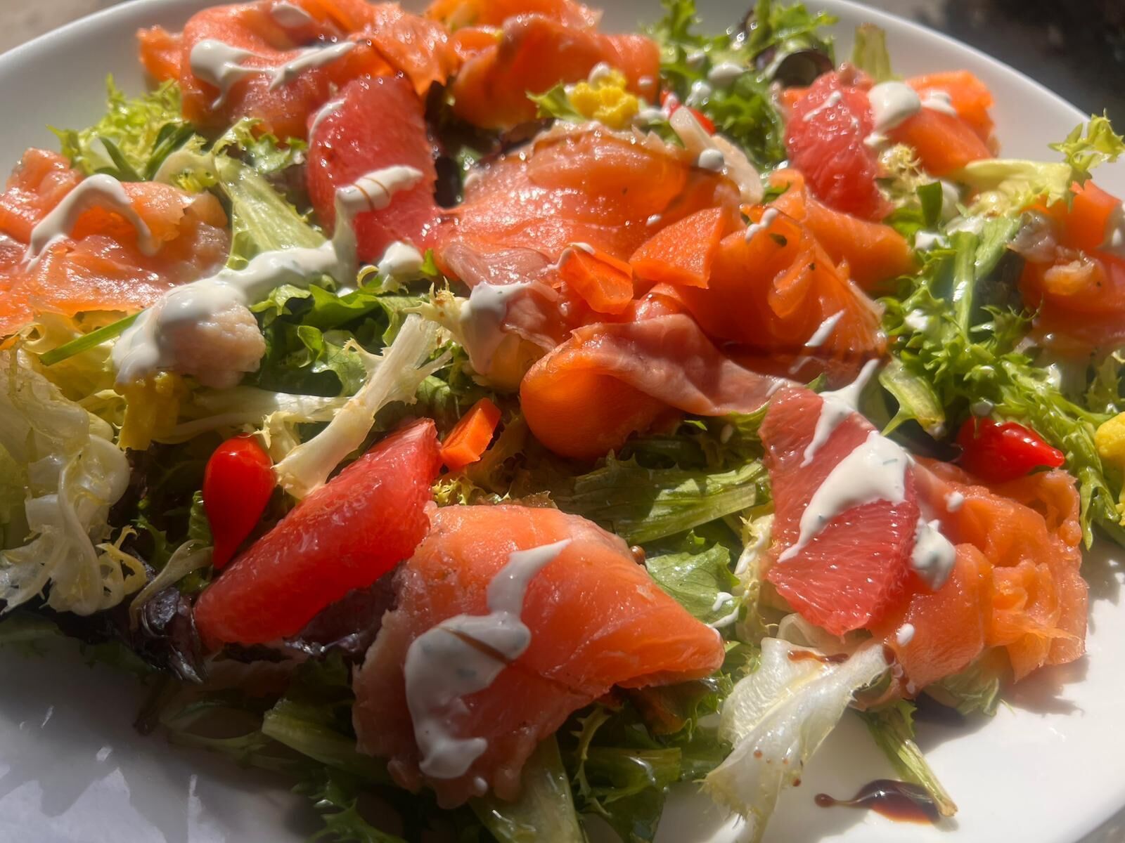 A salad with various vegetables and salmon.