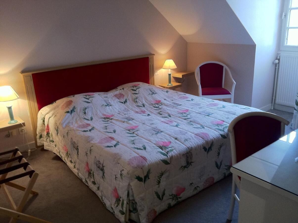 Un dormitorio con cama, una silla, un escritorio y una lámpara.