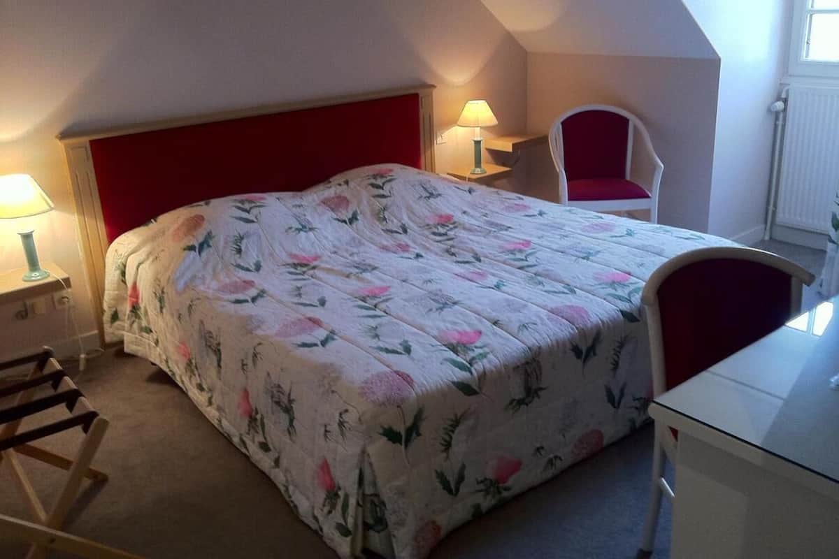 A bedroom with a bed, a chair, a desk, and a lamp.