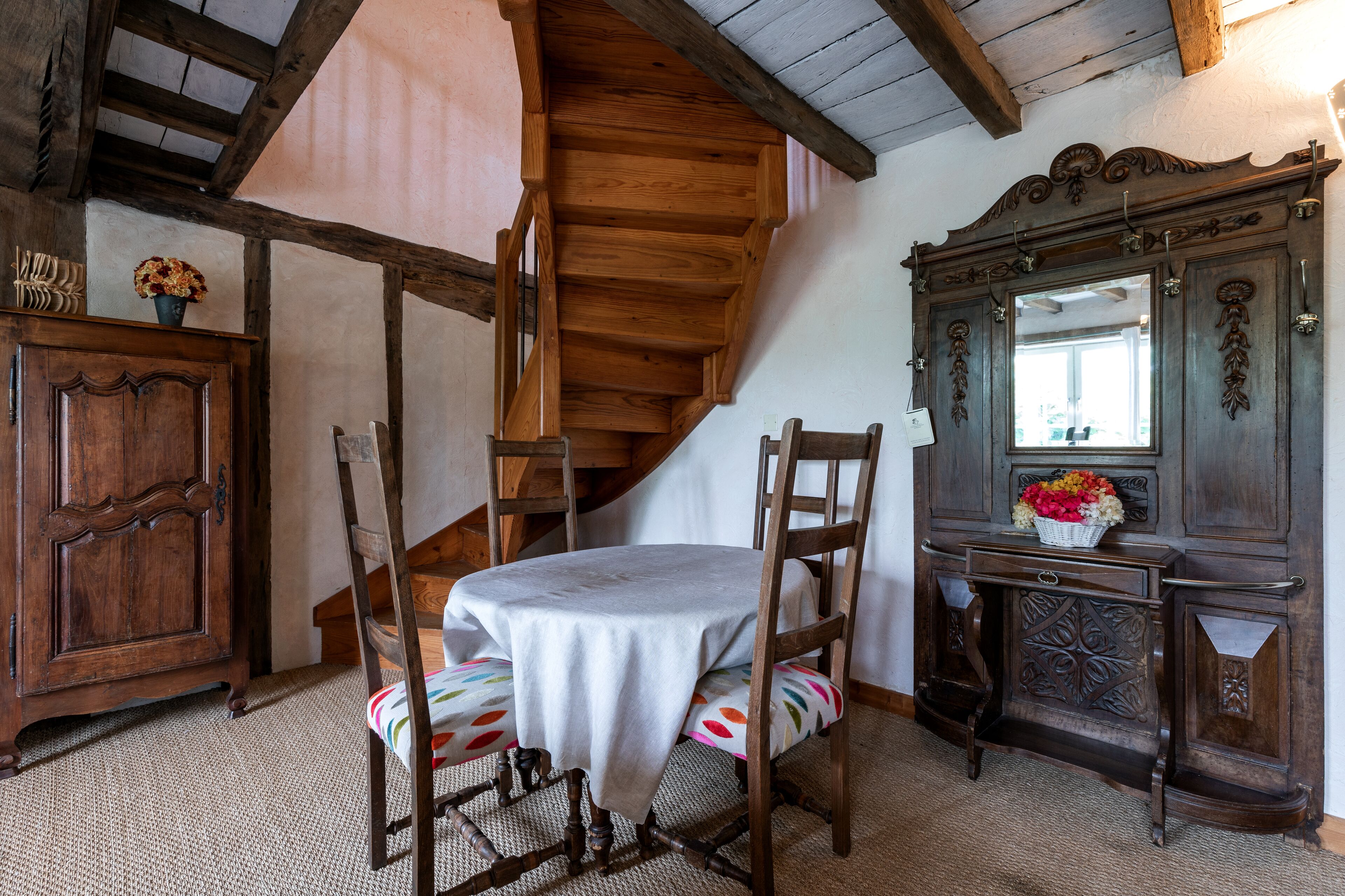 Un comedor de madera con una mesa, sillas, un armario de madera y una escalera.