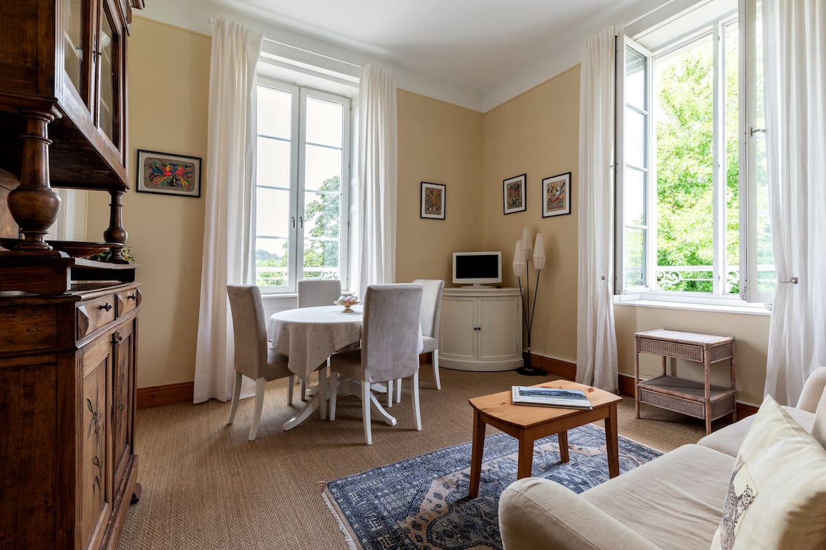 Un salon comprenant une table à manger, des chaises, un canapé, un téléviseur et une bibliothèque.