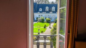 A room with a large window overlooking a well-maintained garden and a blue house.