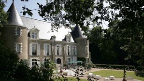 A large, historic building with multiple towers and a well-maintained garden with outdoor seating.