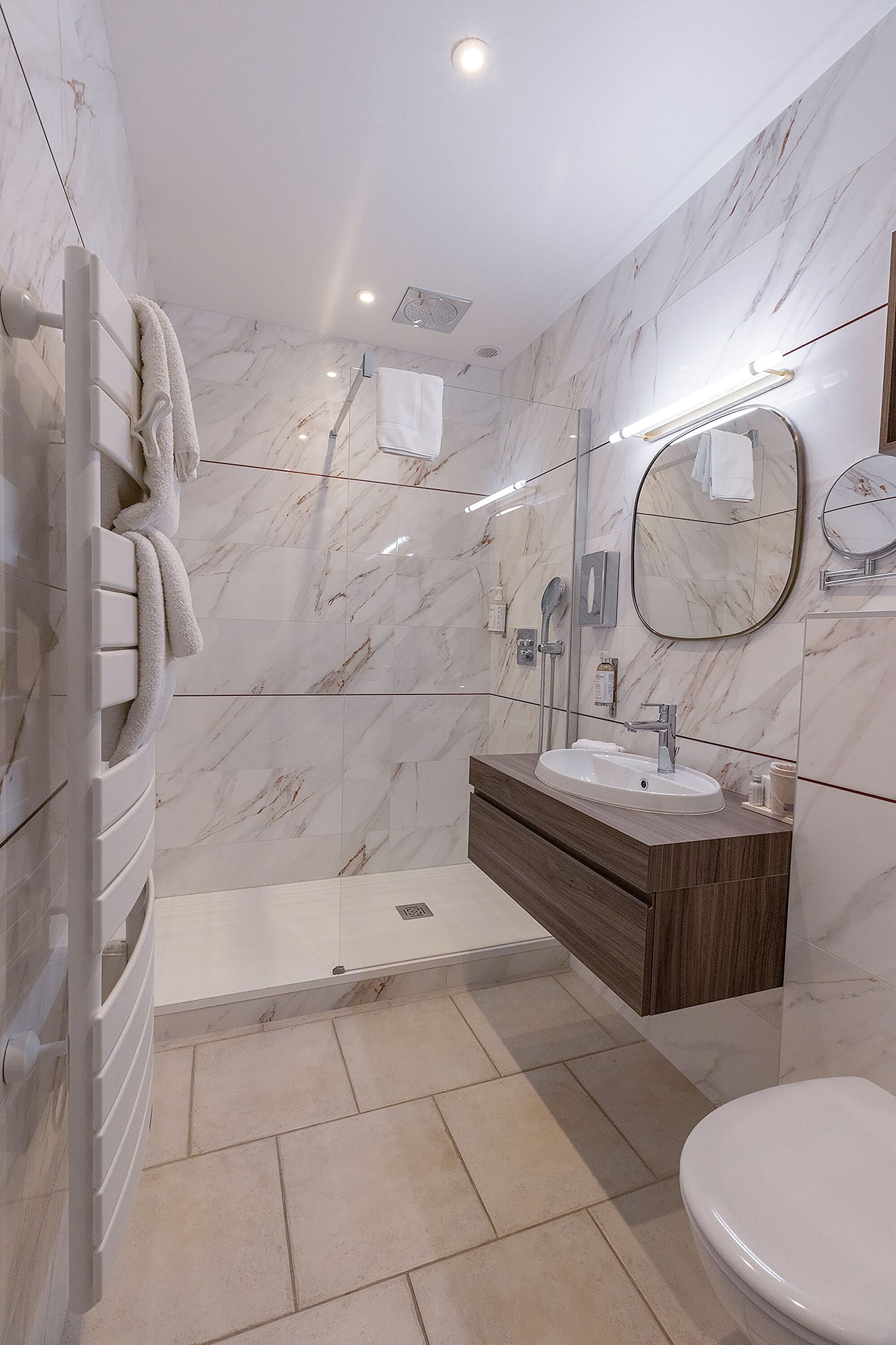 Une salle de bain moderne avec un mur en marbre, une douche intégrée, un meuble-lavabo et des toilettes.