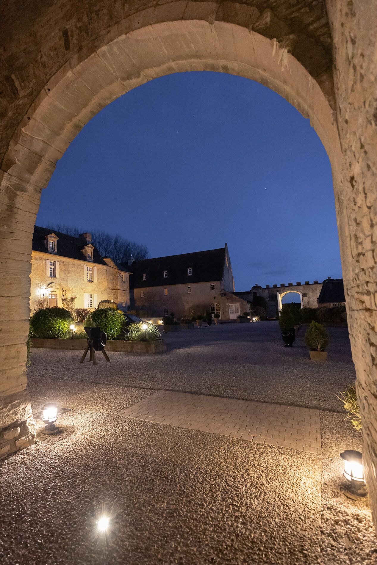 An arched stone structure with a building in the background.