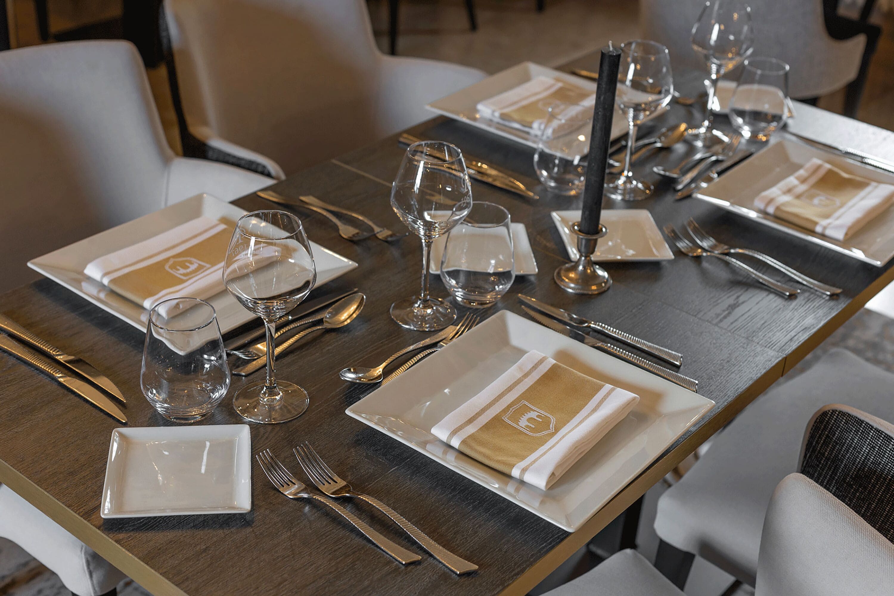 A dining table set with plates, cutlery, and wine glasses, indicating a formal dining arrangement.