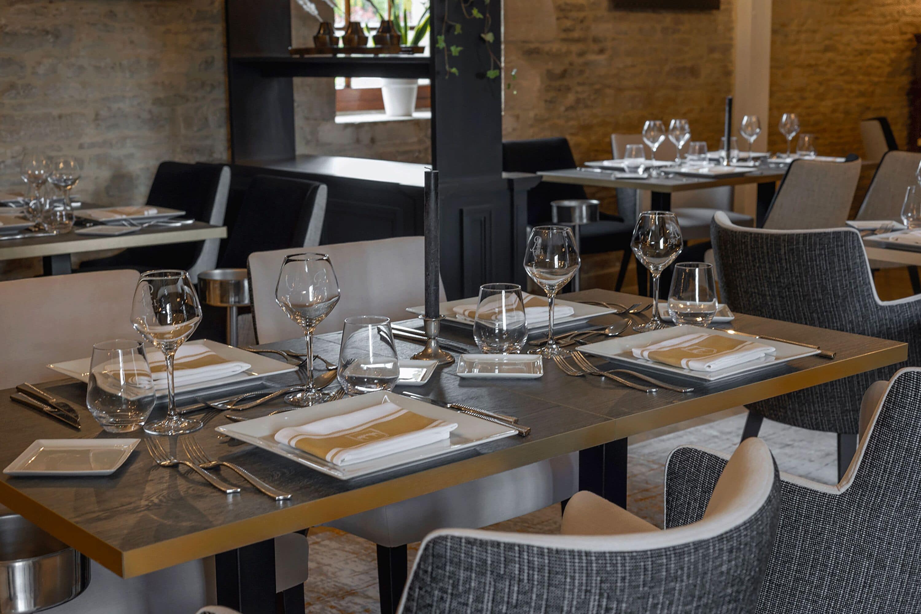 A restaurant with tables set for dining, featuring a modern design with a mix of metal and wood elements.