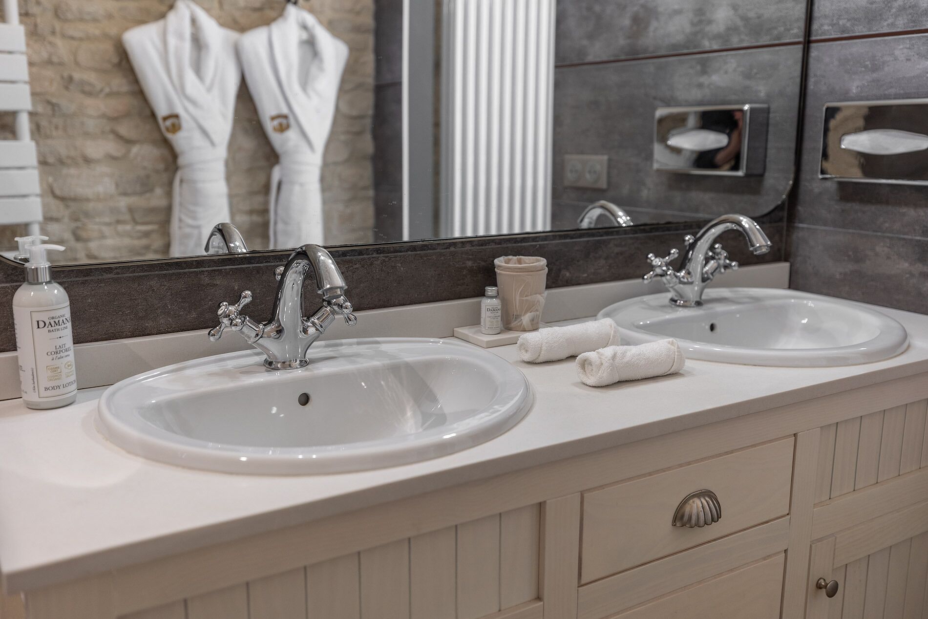 Une salle de bain avec deux lavabos, un miroir et un porte-serviettes.