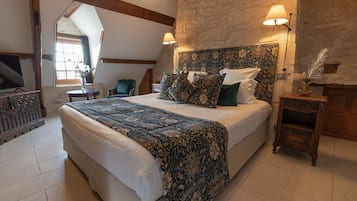 Un dormitorio con una cama grande, un cabecero de madera, una pared de piedra y una mesita de noche con una lámpara.