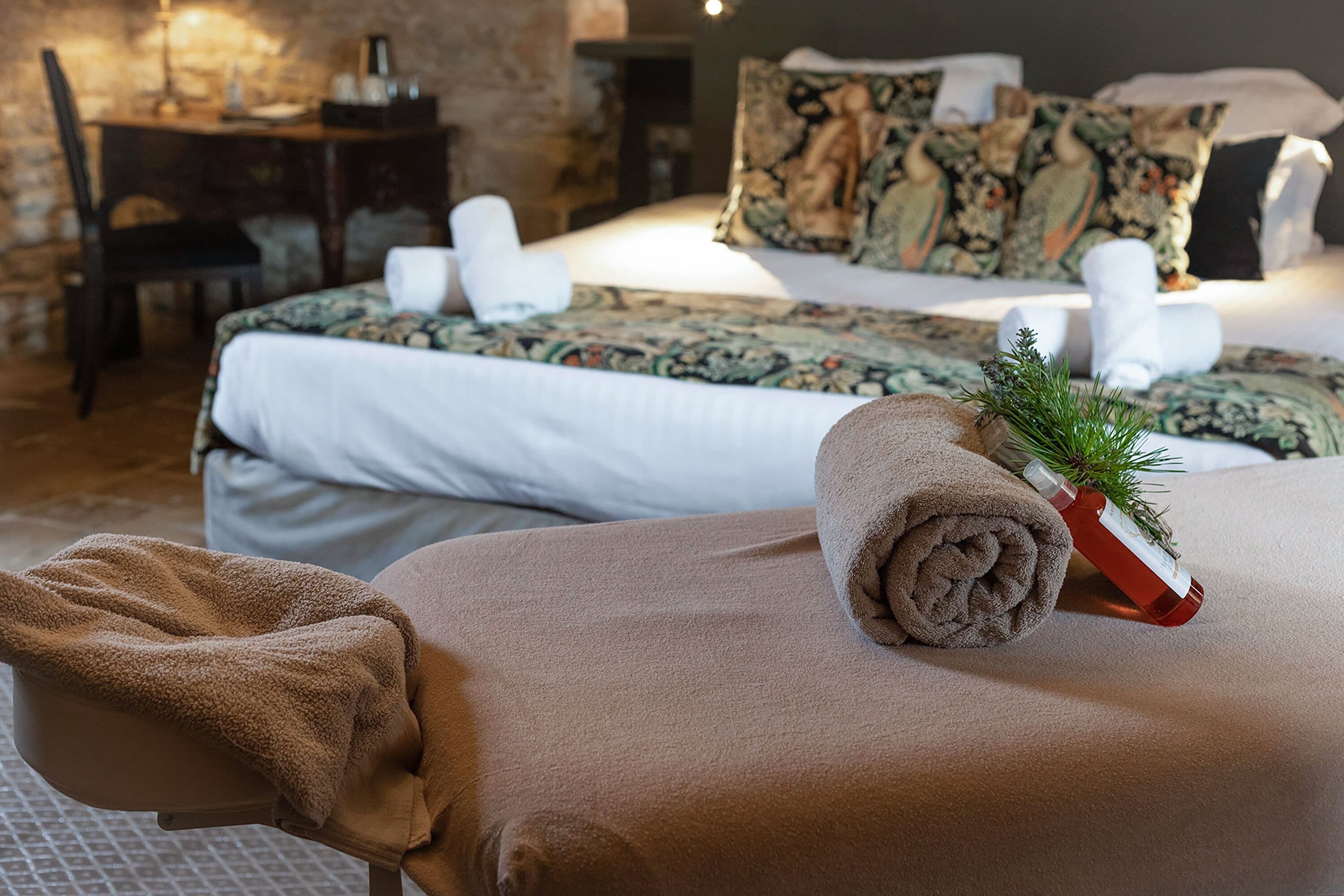 Quarto de hotel com cama, uma cadeira e uma mesinha de cabeceira com abajur.