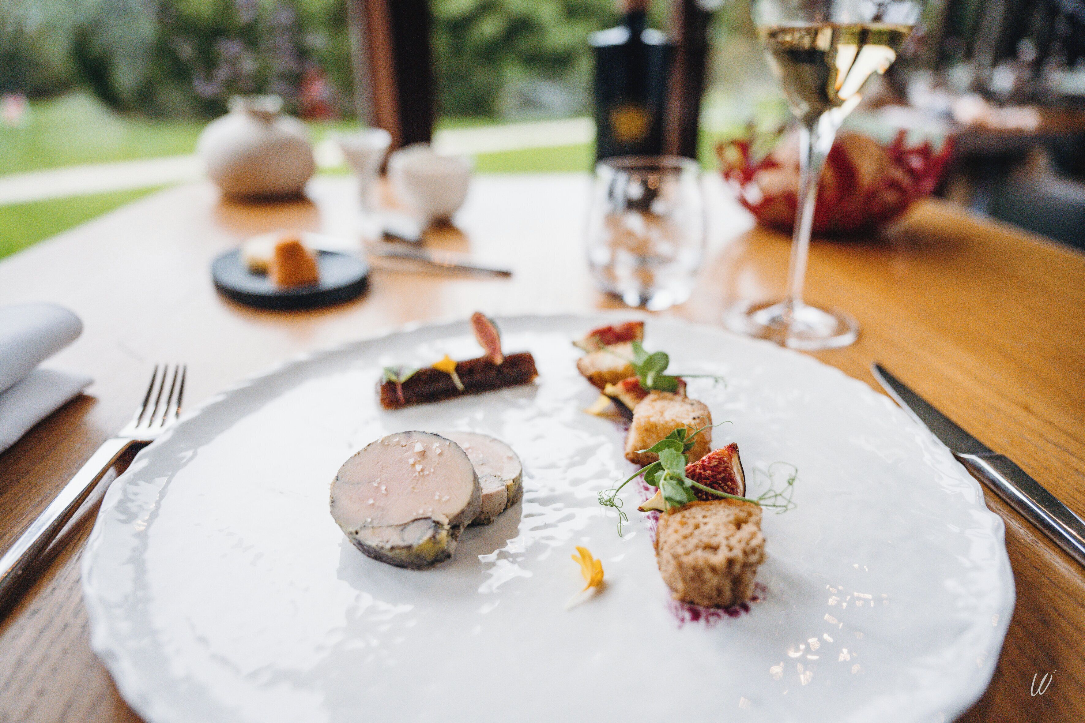 A white plate with various food items, a glass of champagne, and a fork on a wooden table.