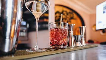 Un ambiente de bar con una copa de martini, una copa de cóctel y un mezclador de cócteles sobre un tapete de bar.