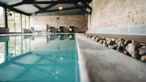 An indoor swimming pool with stone walls and a ceiling with wooden beams.