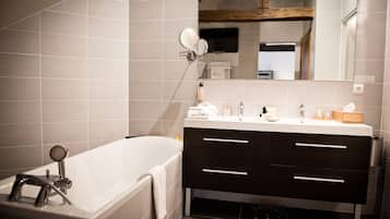 A modern bathroom with a bathtub, dark wooden vanity, and a large mirror.