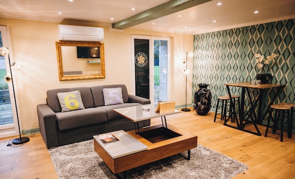 Una sala de estar moderna con un sofá, una mesa de centro y un comedor con taburetes.