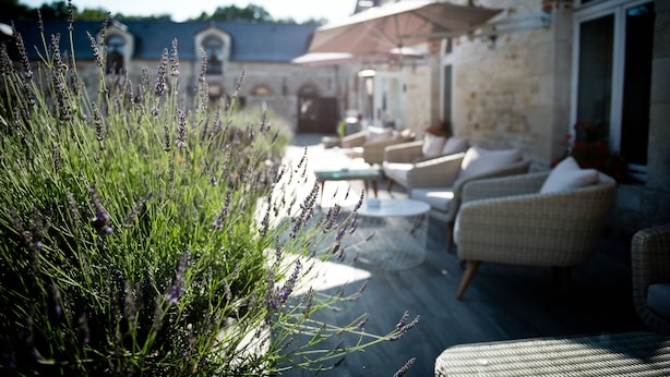 An outdoor seating area with wicker furniture and a stone building in the background.